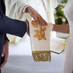 Dłoń księdza błogosławi parę podczas ceremonii, symbolizując przygotowanie do małżeństwa.