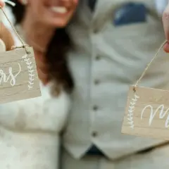 Para Młoda trzyma tabliczki "Mr" i "Mrs", symbolizujące zmianę nazwiska po ślubie.
