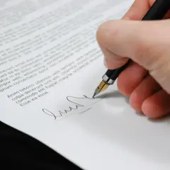 Dłoń z piórem podpisuje dokument. Formalności po ślubie czas zacząć.