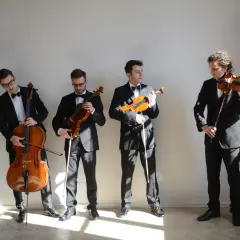 Elegancki kwartet smyczkowy w czarnych garniturach przygotowuje się do występu.