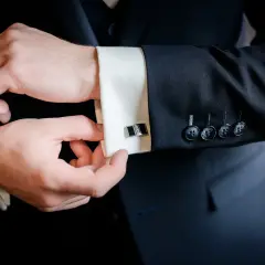 Mężczyzna zapina spinki do mankietów koszuli. Elegancki detal, jak założyć spinki do koszuli.