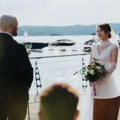 Panna młoda z bukietem czeka na pana młodego. W tle jezioro z łodziami. To ślub jednostronny, ale pełen nadziei.