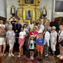 Grupa osób po kursie przedmałżeńskim pozuje do zdjęcia w kościele.