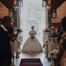 Piękna panna młoda w białej sukni idzie do ołtarza. W kościele trwa ślub kościelny, goście filmują ten ważny moment.
