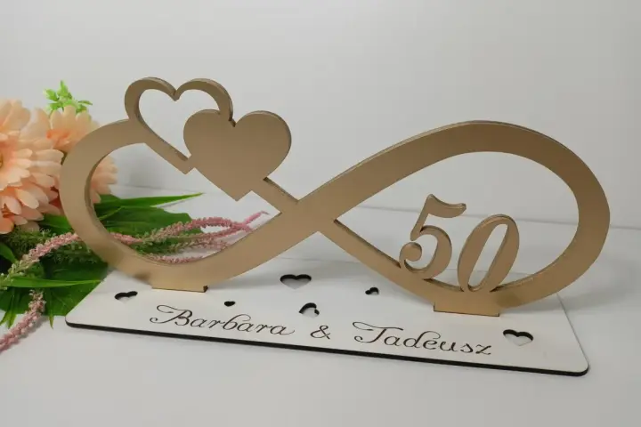 Złota ozdoba na 50 rocznicę ślubu Barbary i Tadeusza. Symbol nieskończoności z sercami i liczbą 50.