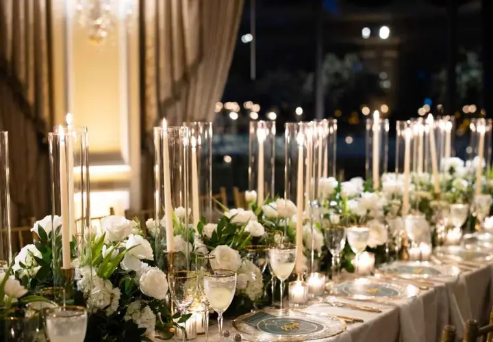 Elegancka dekoracja stołu weselnego z białymi kwiatami i świecami. Sprawdź, jaka jest florystka na wesele cena za takie cuda.