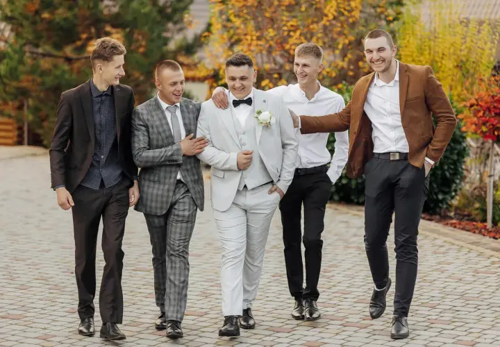 Pięciu panów w eleganckich garniturach, świetny przykład, jak się ubrać na wesele.