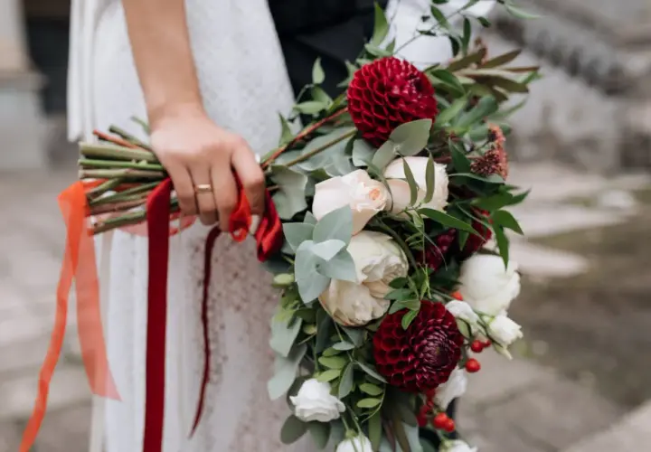 Bukiet ślubny z bordowymi daliami i kremowymi różami, idealny na wrzesień. Czerwone wstążki dodają elegancji.