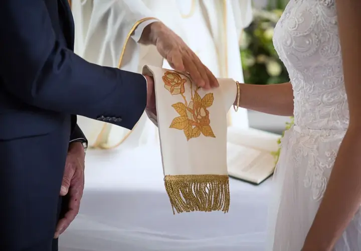 Dłoń księdza błogosławi parę podczas ceremonii, symbolizując przygotowanie do małżeństwa.