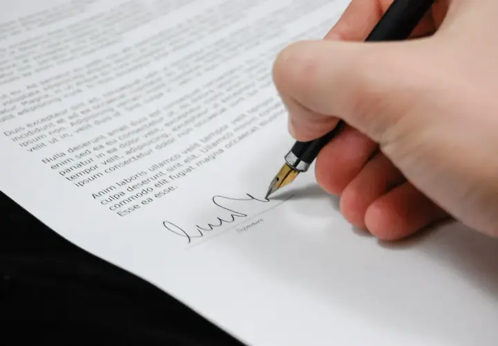 Dłoń z piórem podpisuje dokument. Formalności po ślubie czas zacząć.