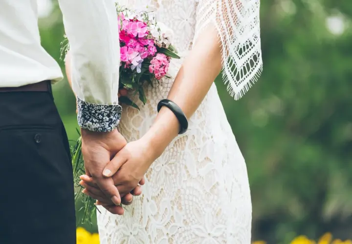 Para weselna trzyma się za ręce, panna młoda w koronkowej sukni z bukietem. Gotowa lista utworów do ZAIKS wesele.