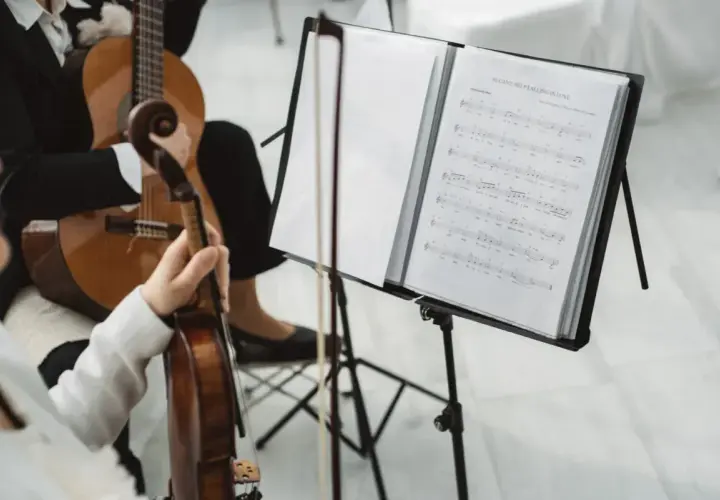 Muzycy grają na gitarze i skrzypcach. Zastanawiasz się, ile kosztuje oprawa muzyczna w kościele?