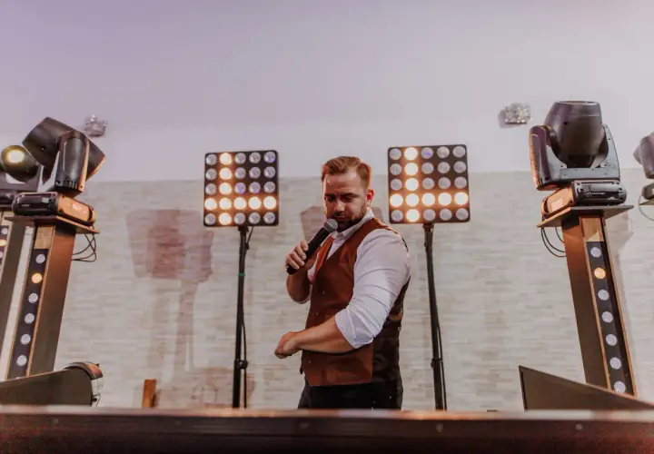 DJ z mikrofonem, otoczony światłami, gotowy do imprezy. Zastanawiasz się, ile kosztuje dj na 18?