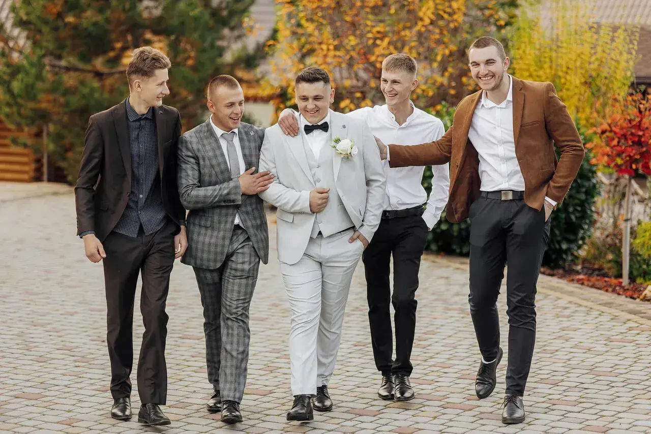 Pięciu panów w eleganckich garniturach, świetny przykład, jak się ubrać na wesele.