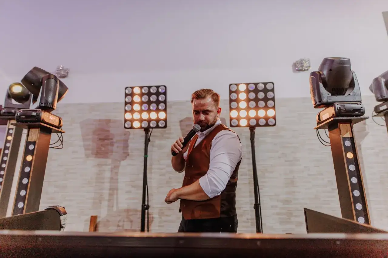 DJ z mikrofonem, przygotowuje się do imprezy. Zastanawiasz się, ile kosztuje dj na 18?