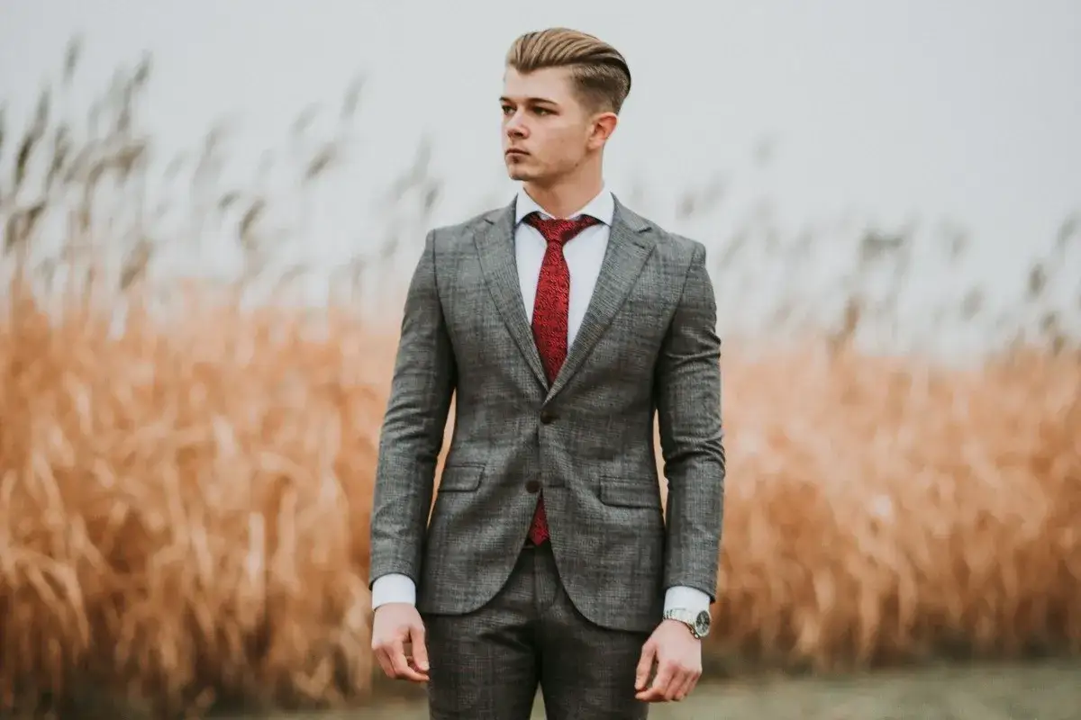 Elegancki pan młody w szarym garniturze w kratę i czerwonym krawacie. Idealny wybór, jaki garnitur dla pana młodego na wesele.